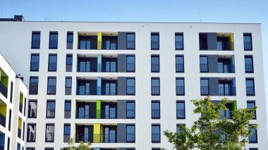 Gündüz gözüyle modern yerleşim yerinin dış tarafında. Mavi gökyüzü olan güneşli bir günde modern apartman binaları. Modern bir apartmanın cephesi