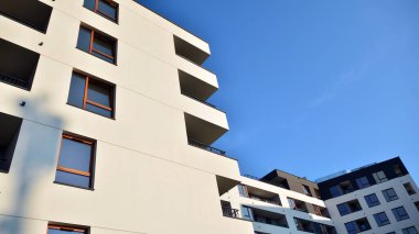 Gündüz gözüyle modern yerleşim yerinin dış tarafında. Mavi gökyüzü olan güneşli bir günde modern apartman binaları. Modern bir apartmanın cephesi