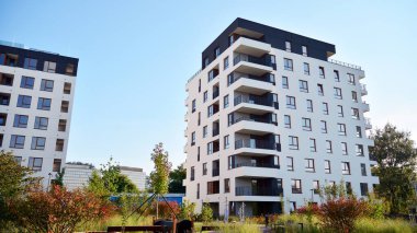 Gündüz gözüyle modern yerleşim yerinin dış tarafında. Mavi gökyüzü olan güneşli bir günde modern apartman binaları. Modern bir apartmanın cephesi