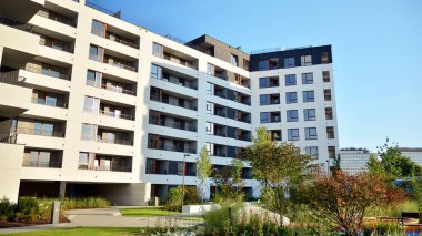 Gündüz gözüyle modern yerleşim yerinin dış tarafında. Mavi gökyüzü olan güneşli bir günde modern apartman binaları. Modern bir apartmanın cephesi