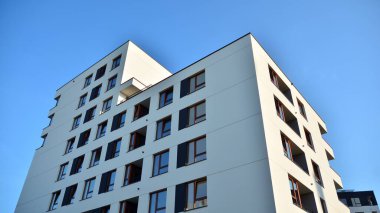 Gündüz gözüyle modern yerleşim yerinin dış tarafında. Mavi gökyüzü olan güneşli bir günde modern apartman binaları. Modern bir apartmanın cephesi