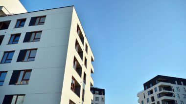 Gündüz gözüyle modern yerleşim yerinin dış tarafında. Mavi gökyüzü olan güneşli bir günde modern apartman binaları. Modern bir apartmanın cephesi