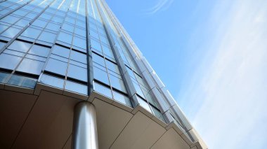 Mavi gökyüzünün altındaki tonlu cam ve çelik yapılardan yapılmış mavi perde duvarı. Bir binanın parçası..