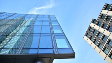 Mavi gökyüzünün altındaki tonlu cam ve çelik yapılardan yapılmış mavi perde duvarı. Bir binanın parçası..