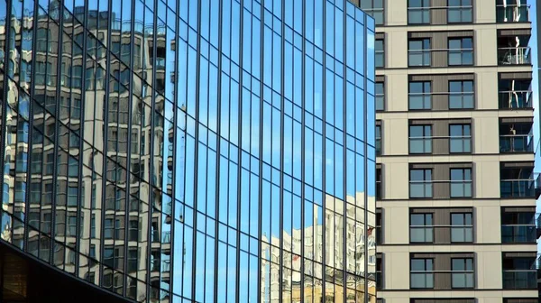 Blue curtain wall made of toned glass and steel constructions under blue sky. A fragment of a building.