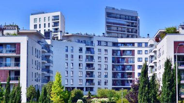 Balkonları ve yeşillikleri olan modern bir apartman. Yazın güzel bir emlak binası manzarası. Ağaçlar ve otlarla dolu bir yürüyüş alanı. Yeşil alandaki modern konut binaları. 