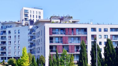 Balkonları ve yeşillikleri olan modern bir apartman. Yazın güzel bir emlak binası manzarası. Ağaçlar ve otlarla dolu bir yürüyüş alanı. Yeşil alandaki modern konut binaları. 