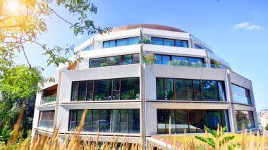 Balkonları ve yeşillikleri olan modern bir apartman. Yazın güzel bir emlak binası manzarası. Ağaçlar ve otlarla dolu bir yürüyüş alanı. Yeşil alandaki modern konut binaları. 