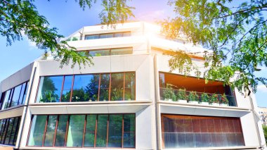 Balkonları ve yeşillikleri olan modern bir apartman. Yazın güzel bir emlak binası manzarası. Ağaçlar ve otlarla dolu bir yürüyüş alanı. Yeşil alandaki modern konut binaları. 