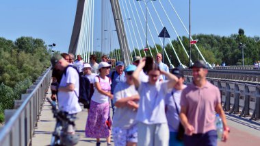 Varşova, Polonya. 15 Ağustos 2025. Swietokrzyski Köprüsü 'nü geçen turistler ve sakinler kalabalıktı. Hafta sonu köprüden birlikte geçen bir grup insan.. 
