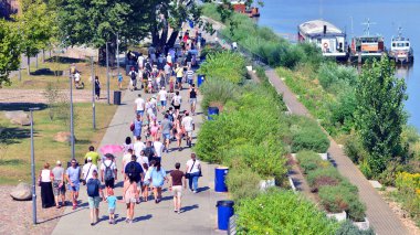 Varşova, Polonya. 15 Ağustos 2025. Vistula nehri boyunca gezinti yapan turistler ve sakinler kalabalıktı. Hafta sonu gezintiye çıkan bir grup insan birlikte yürüyor..