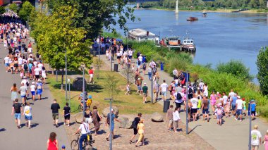 Varşova, Polonya. 15 Ağustos 2025. Vistula nehri boyunca gezinti yapan turistler ve sakinler kalabalıktı. Hafta sonu gezintiye çıkan bir grup insan birlikte yürüyor..