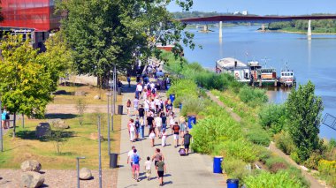 Varşova, Polonya. 15 Ağustos 2025. Vistula nehri boyunca gezinti yapan turistler ve sakinler kalabalıktı. Hafta sonu gezintiye çıkan bir grup insan birlikte yürüyor..