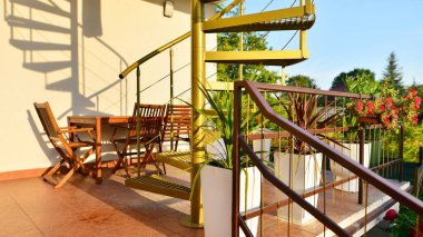 Terasta, saksılarda bitki ve bitkiler olan, çelik spiral altın merdivenler..