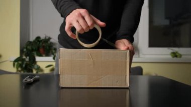 Evde bir paket paketlemek, ellerinizi kapamak, konforlu iç kısımda nakliye için paketler hazırlamak.