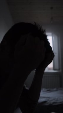 Depresyon ve tükenme. Adam evde oturmuş başını tutup saçını çekiyor endişeli siluet yaşam tarzı akıl sağlığı kavramını strese sokuyor..