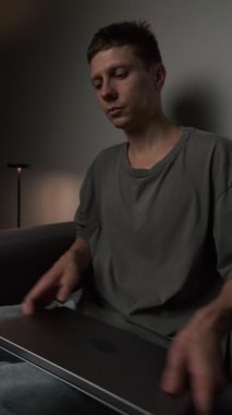 Adam dizüstü bilgisayar işini kanepede bitiriyor, ayağa kalkıyor ve aniden sırt ağrısı çekiyor. Sıcak, minimalist bir oturma odası ve sıcak bir atmosferi var..