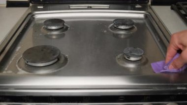 Evde gaz sobası temizliyorum. Temizlik ve hijyen için mutfak yüzeyini yeşil bezle silmek. Ev işleri ve ev bakımı