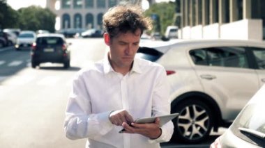Şehrin caddesinde trafik ve ağır çekimde tabletle çalışan adam