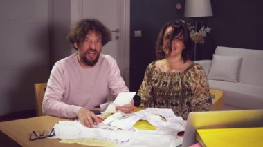 Üzgün karı koca kameraya bakıyor. Ödenecek bir sürü fatura var, ağır çekimde.