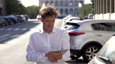 Şehir yavaş gün batımında tablet ile sokakta çalışan serin iş adamı