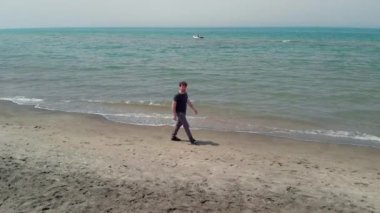 Mutlu adam okyanusun dron atış germe önünde sahilde yürüyüş