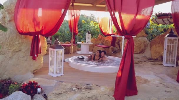 情侣在爱拥抱室内按摩浴缸在日落慢动作与太阳光在相机耀斑 — 图库视频影像