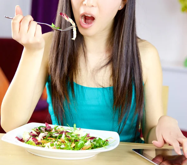 Happy asian woman eating salad at home checking tablet closeup — Stock Photo, Image