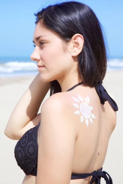 Mujer joven seria con el sol dibujado en su espalda mirando los horizontes. cuidado de la piel, protector solar — Foto de Stock