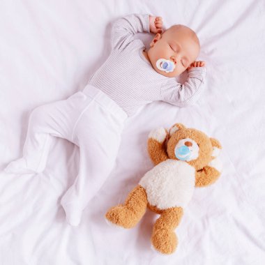 high angle view of adorable little boy with baby dummy sleeping with teddy bear  clipart