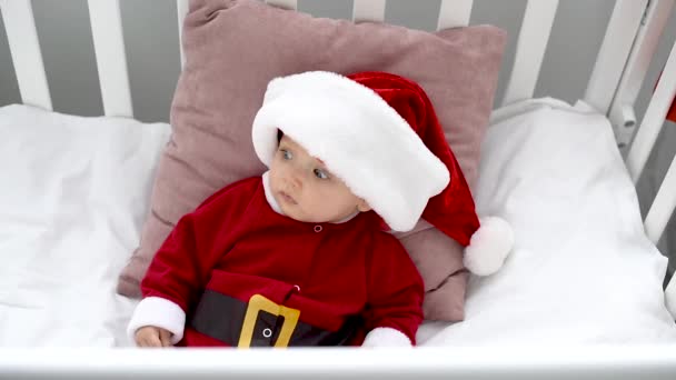 Surprised Adorable Baby Santa Costume Looking Away Sitting Crib Home — Stock Video