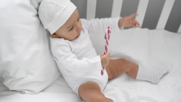 可爱的婴儿玩圣诞糖果甘蔗在婴儿床在家 — 图库视频影像