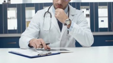 Dijital tablet ve klinikte tanı yazma beyaz montlu erkek doktor