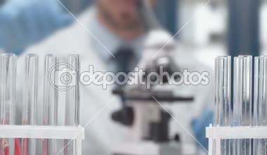 zemin üzerine laboratuvarında deney sırasında mikroskop kullanarak erkek bilim adamı ile tüplerin seçici odak