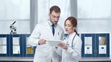 kadın ve erkek doktorlar beyaz kat dijital tablet klinikte kullanma olarak 