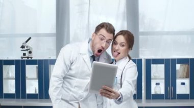 kadın ve erkek doktorlar çeşitli yüz ifadeleri Kliniği dijital tablet selfie çekerken gösterilen 