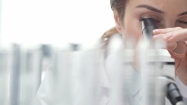 Beyaz önlük laboratuvar mikroskop aramak içinde kadın bilim adamının seçici odak