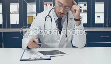 yakışıklı erkek doktor dijital tablet ve klinikte tanı yazma beyaz ceket