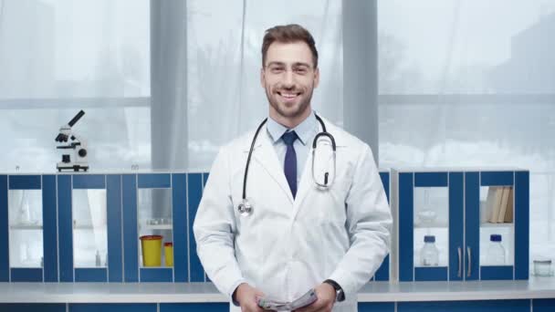 Médico Masculino Casaco Branco Olhando Para Câmera Sorrindo Jogando Dinheiro — Vídeo de Stock