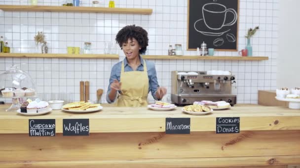 美丽的微笑非洲裔美国女咖啡馆老板在围裙跳舞背后的柜台与甜点 — 图库视频影像