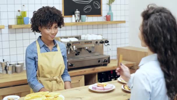 女性をカフェでクレジット カードで払いながらターミナルを持って美しいアフリカ系アメリカ人の女性レジ係 — ストック動画