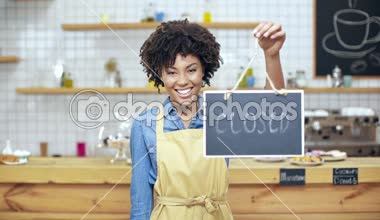 ağır çekim güzel Afrikalı-Amerikalı kadın Kafe sahibi işareti açık-kapalı tutarak ve kameraya bakarak önlük