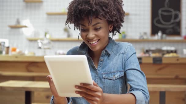 セレクティブ フォーカス デジタル タブレットを使用して カフェで笑顔美しいのアフリカ系アメリカ人の女性のお客様 — ストック動画