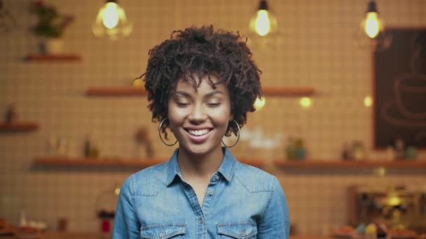 在牛仔衬衫上看着咖啡馆的相机的美丽的微笑的非洲裔美国女人的选择性焦点 — 图库视频影像