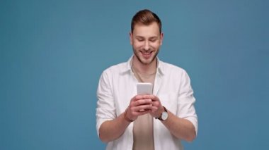 gülümseyen ve mavi kopya alanı ile izole smartphone kullanarak yakışıklı adam