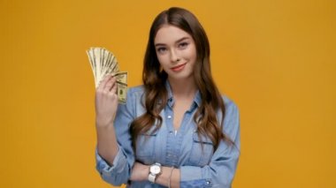 Kameraya bakarak, Doları banknot sallayarak ve üzerinde izole sarı gülümseyen güzel kız