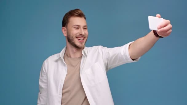ハンサムな男の笑みを浮かべて 青に分離されたスマート フォンに Selfie — ストック動画