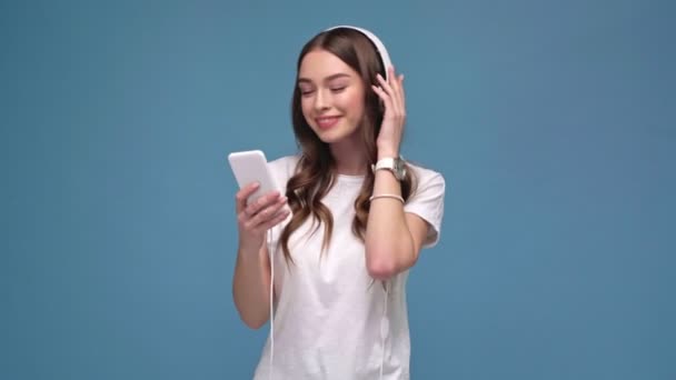 Szép Lány Fejhallgató Smartphone Zenét Hallgatni Táncolni Mosolyogva Elszigetelt Kék — Stock videók