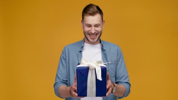 ギフト用の箱 黄色の分離カメラ目線の幸せのハンサムな男 — ストック動画