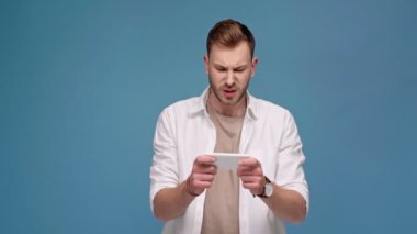 Mavi izole smartphone üzerinde konsantre yakışıklı palying oyun